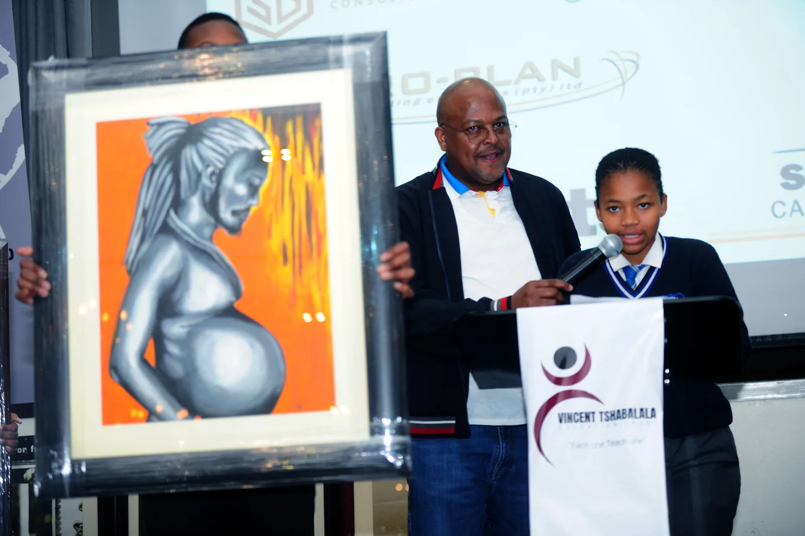 A learner speaking beside a framed artwork at the Trust’s fundraising auction